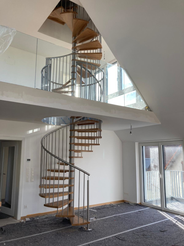 Wendeltreppe mit Eichenstufen und Edelstahlgeländer über zwei Geschoße